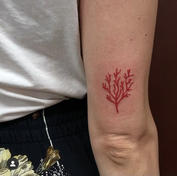 a woman with a red tattoo on her arm that has a plant design on it