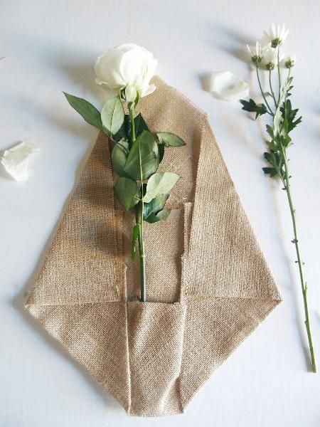 white flowers are sitting on top of a linen napkin and some green leaves next to it