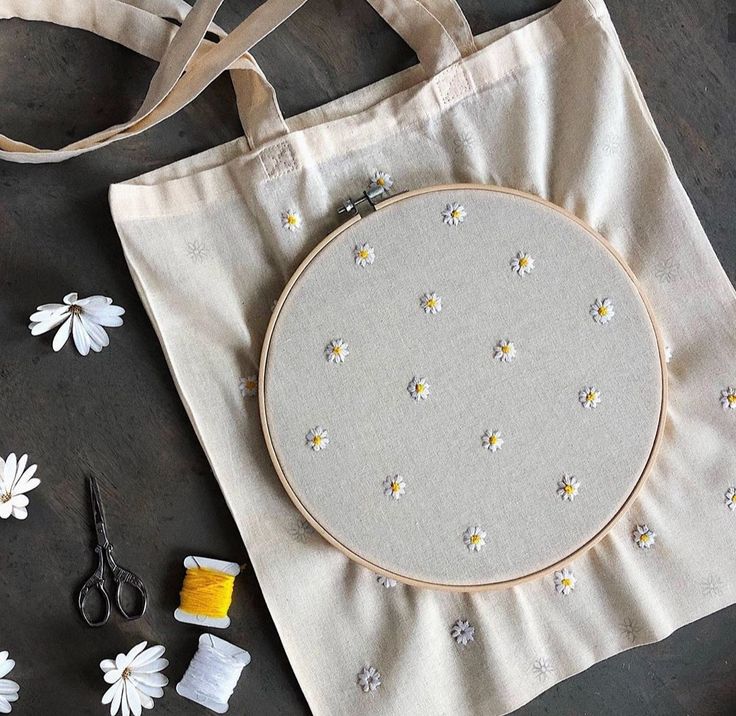 a white bag with flowers on it next to scissors, thread and other crafting supplies