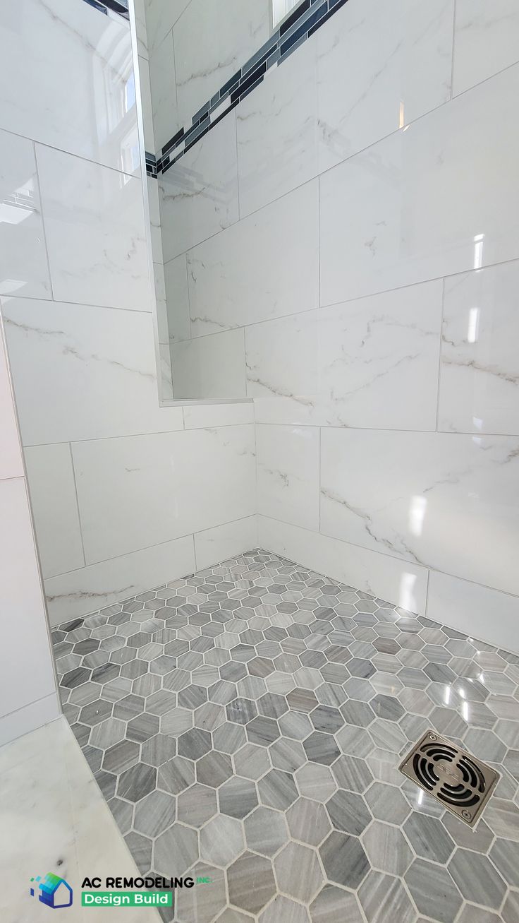 a bathroom with white marble tile and hexagonal pattern on the shower floor is shown