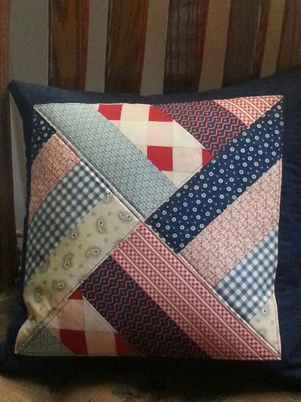 a decorative pillow on a wooden chair with blue and red fabric around the edges that have been stitched together