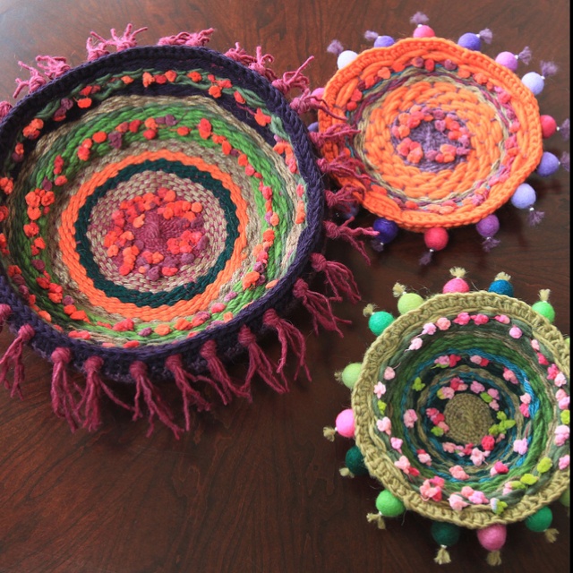 three crocheted baskets sitting on top of a wooden table