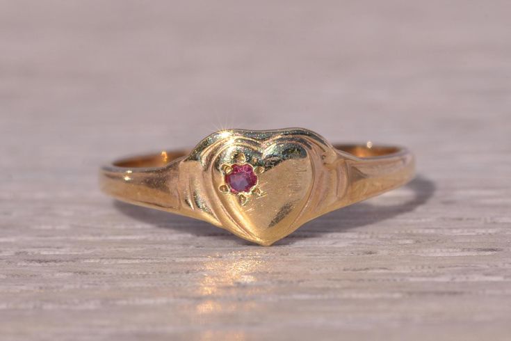 This stunning piece, known as The Heartfelt Ruby, features a captivating natural ruby set at the center of a heart motif. The natural ruby adds a touch of color and elegance, making it a delightful piece for any collection. The ring is crafted in yellow gold and is currently a finger size 4 but can be adjusted to any finger size for an additional charge upon request, ensuring a perfect fit. Love this piece, but don't have the money to spend right now? We offer FREE layaway on every item in our shop. With just 20% down, take one full year (interest-free) to pay off your new jewelry! There are no hidden fees or charges, ever. For more information on our layaway policy, please contact us. Each piece has been hand-selected and meticulously identified and graded by a Graduate Gemologist who has Fine Ruby Heart-shaped Jewelry, Fine Ruby Heart Jewelry, Yellow Gold Heart Cut Ruby Jewelry, Heart Cut Ruby Jewelry In Yellow Gold, Heirloom Heart-shaped Gemstone Ring, Heirloom Heart Ring With Birthstone For Valentine's Day, Valentine's Day Heirloom Heart Ring With Birthstone, Heart-shaped Ruby Jewelry For Wedding, Heart-shaped Ruby Wedding Jewelry