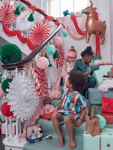 two young children are sitting on the stairs decorated with christmas decorations and gifts for their holiday party