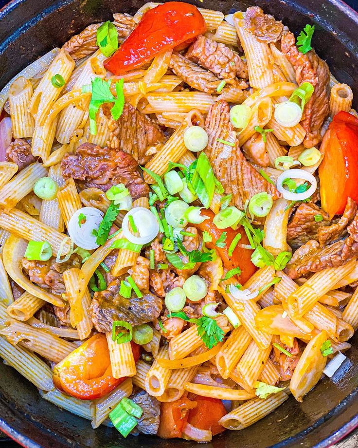 a skillet filled with pasta, meat and vegetables