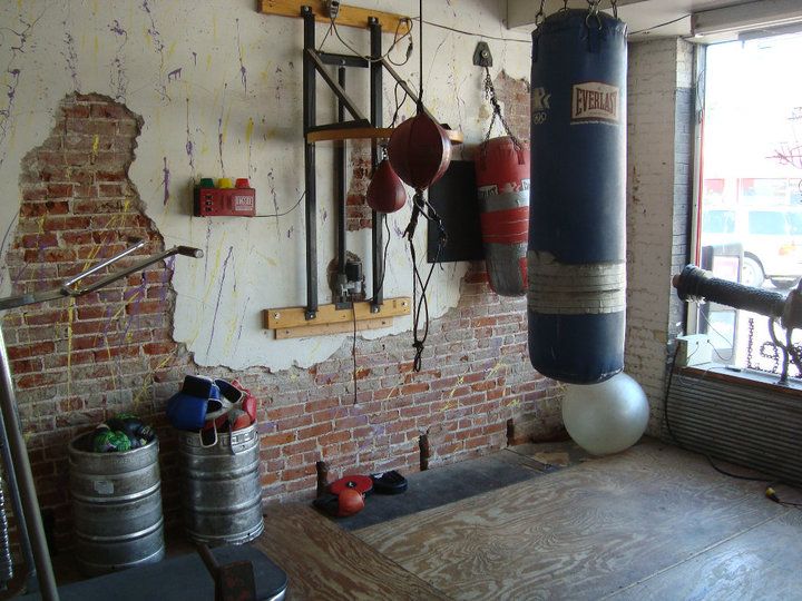 an old brick wall with boxing gloves hanging from it's hooks and punching bag