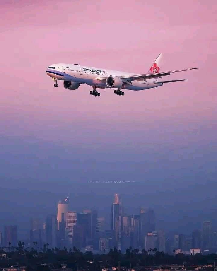 an airplane is flying in the sky over some buildings and skyscrapers at dusk time