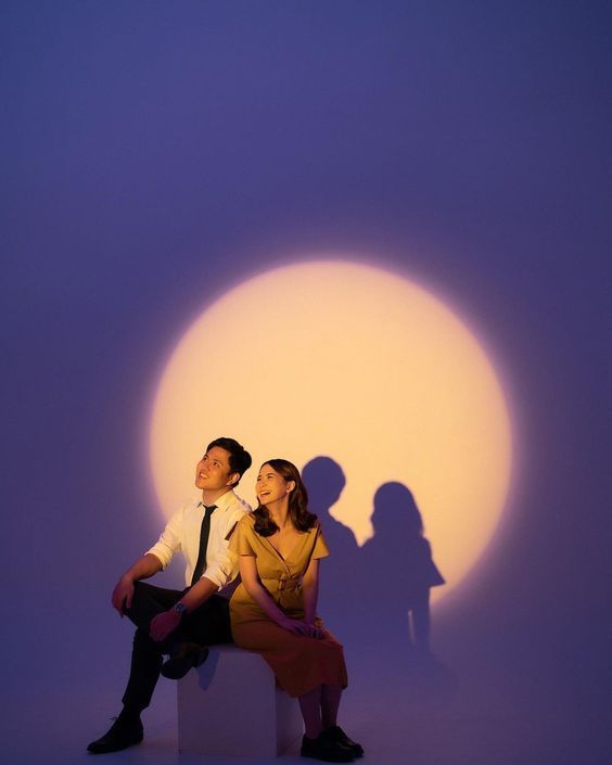 a man and woman sitting next to each other in front of a shadow on the wall