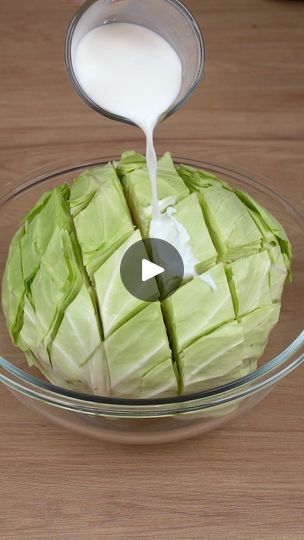 a bowl filled with lettuce and milk being poured on top of the cabbage