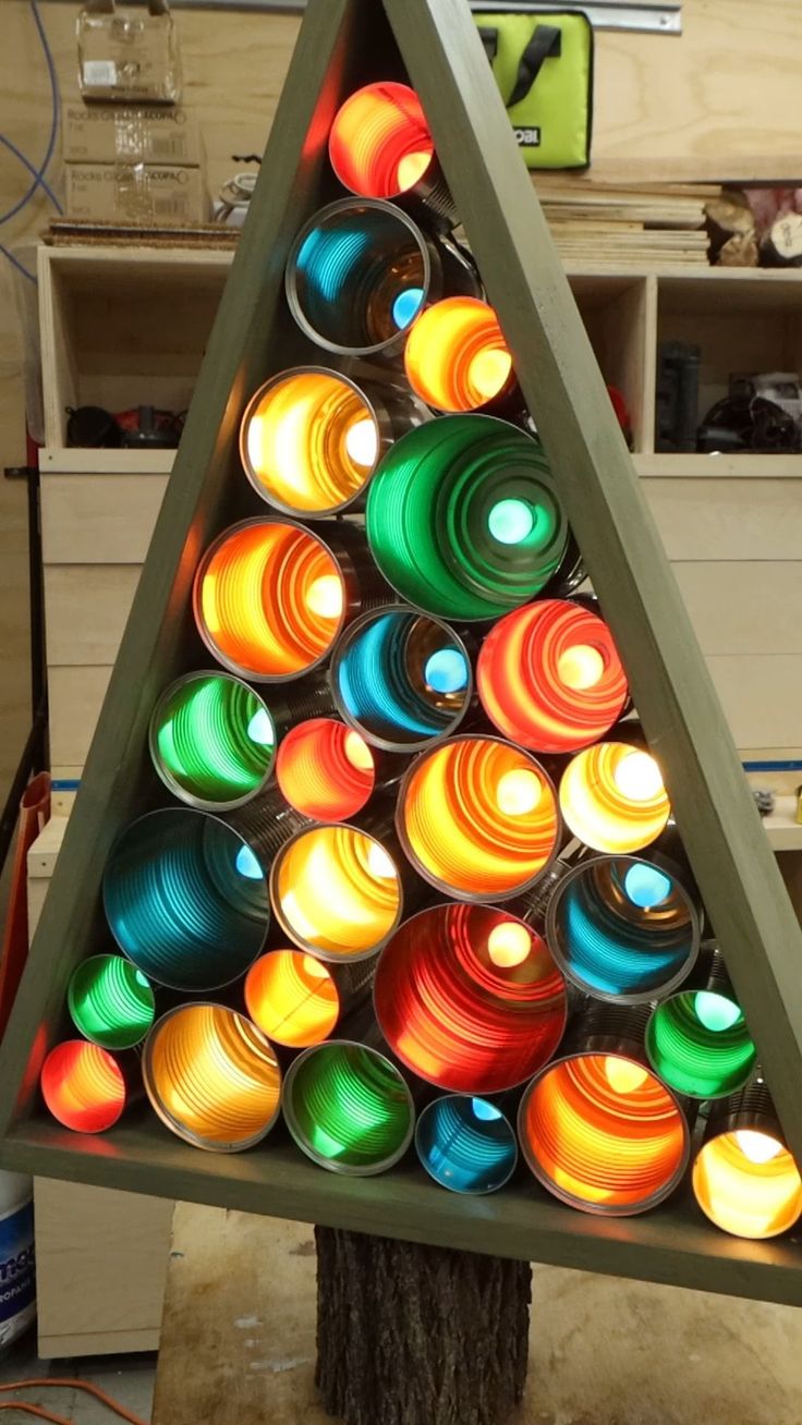 a christmas tree made out of cans is shown in the shape of a triangle with lights on it