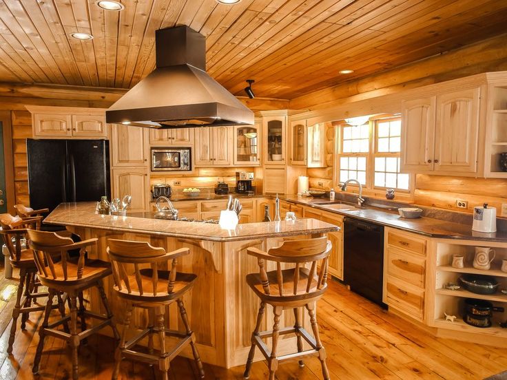 a large kitchen with wooden floors and an island in the middle, surrounded by bar stools