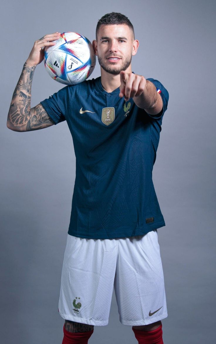 a man holding a soccer ball in his right hand and pointing at it with both hands