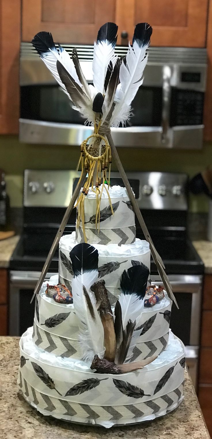 a three tiered cake decorated with feathers and arrows is on a kitchen countertop