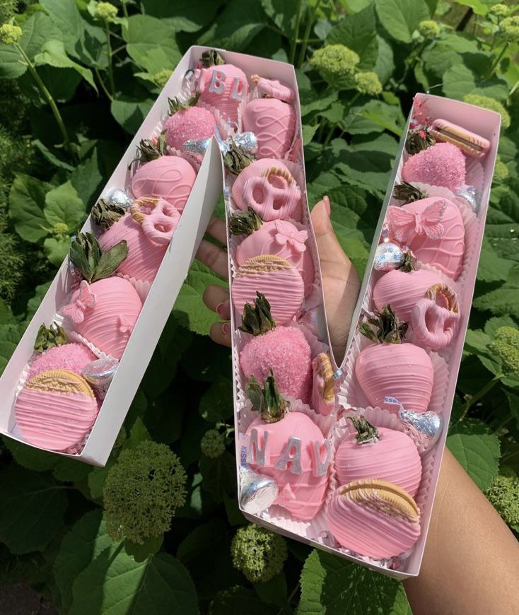 two boxes filled with pink frosted strawberries in the shape of letters and numbers