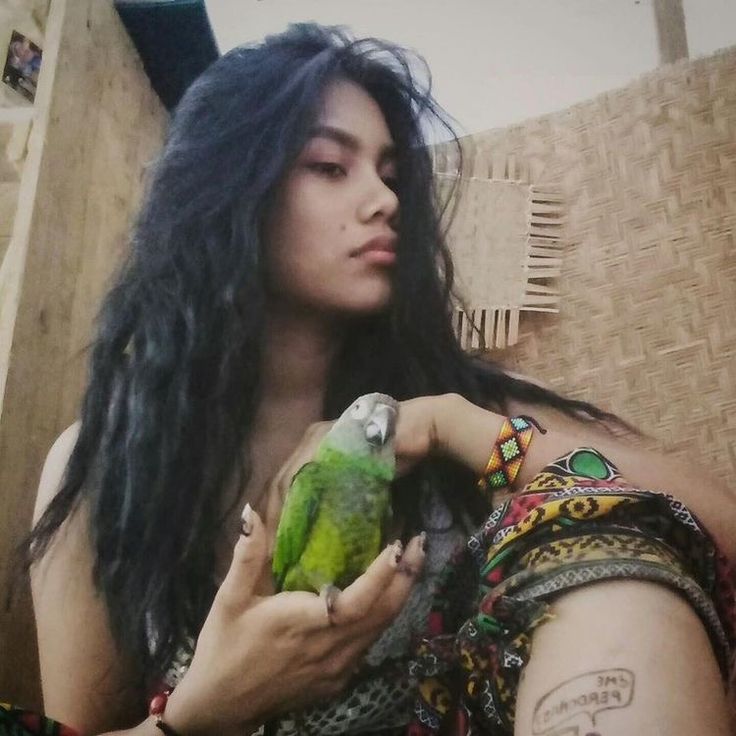 a woman with long black hair holding a green bird