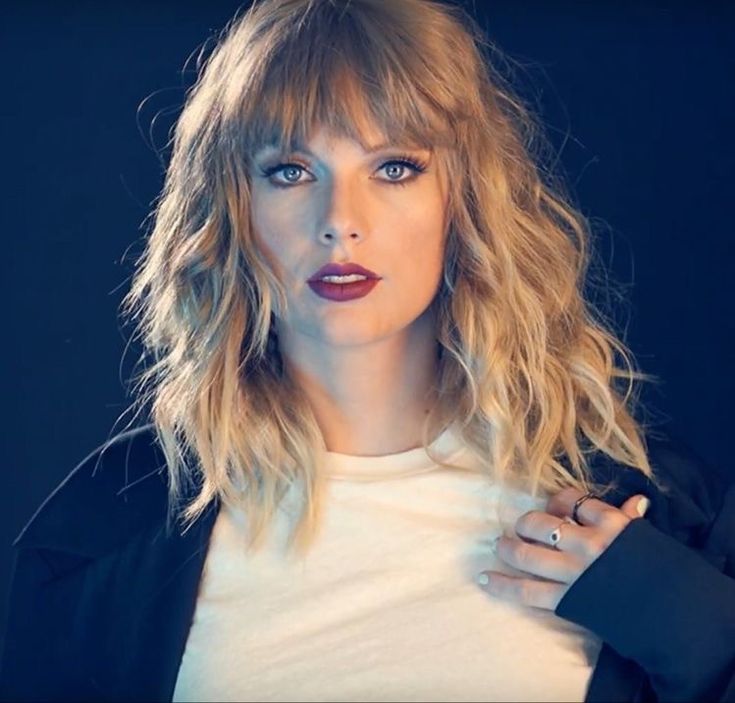 a woman with blonde hair wearing a black jacket and white shirt is posing for the camera