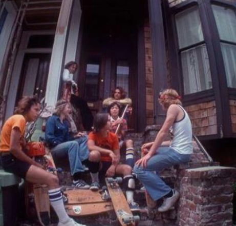 a group of young people sitting on the steps in front of a house with their skateboards