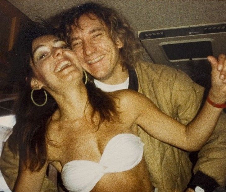 a man and woman posing for a photo in the back seat of a car with their arms around each other