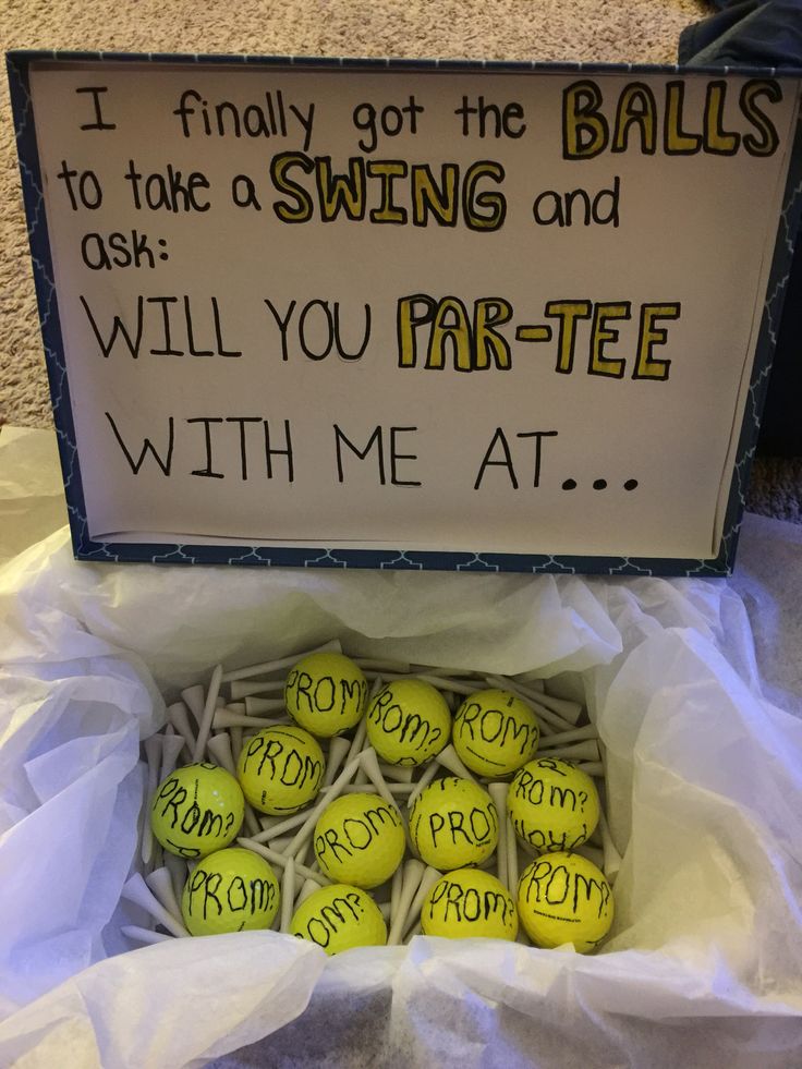 a box filled with tennis balls sitting on top of a floor next to a sign