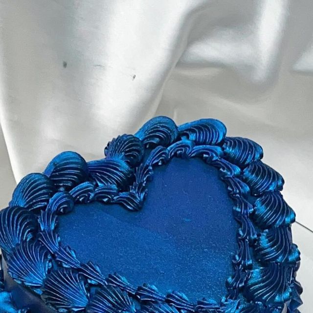 a blue heart shaped cake sitting on top of a table