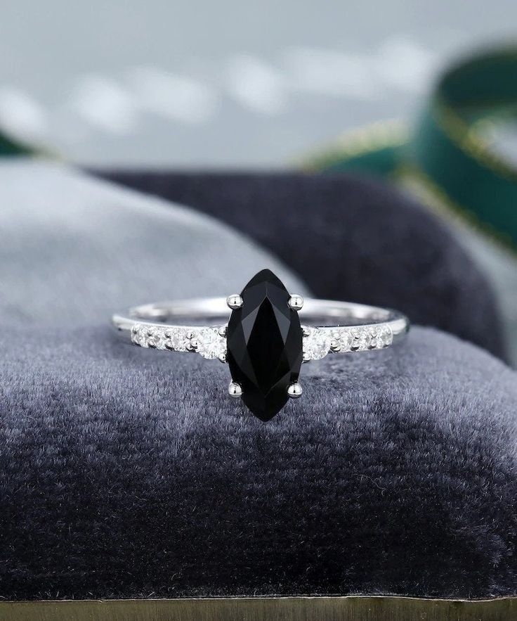 a black diamond ring sitting on top of a velvet cushion