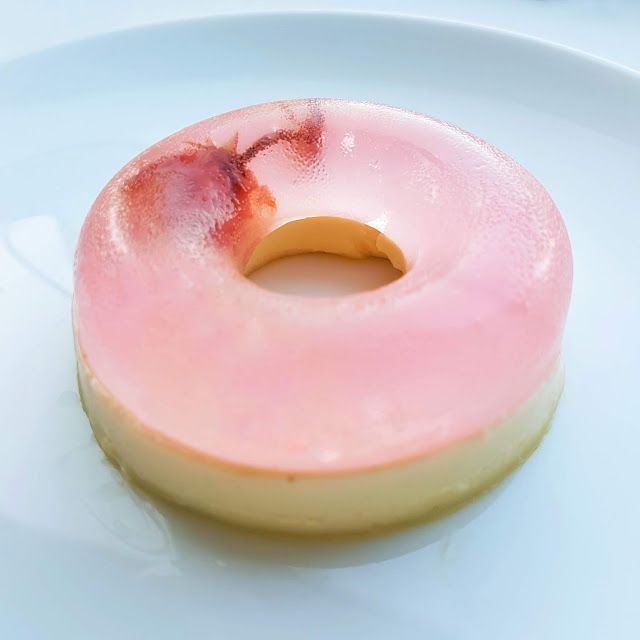 a donut with pink icing on a white plate