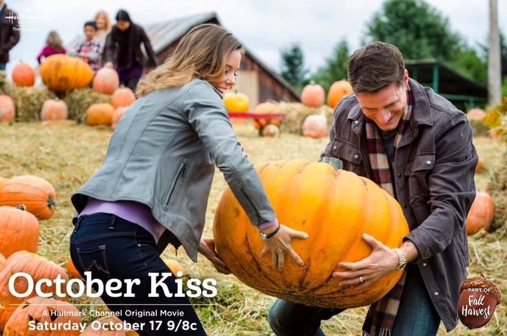 a man and woman picking up a large pumpkin