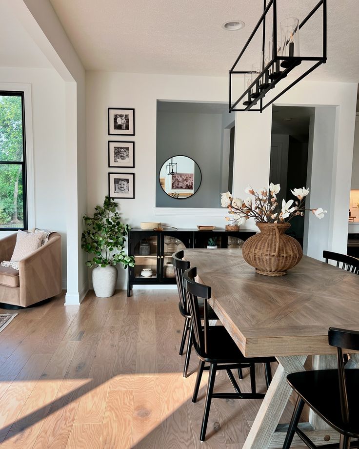 the dining room table is surrounded by black chairs and wooden tables with vases on them