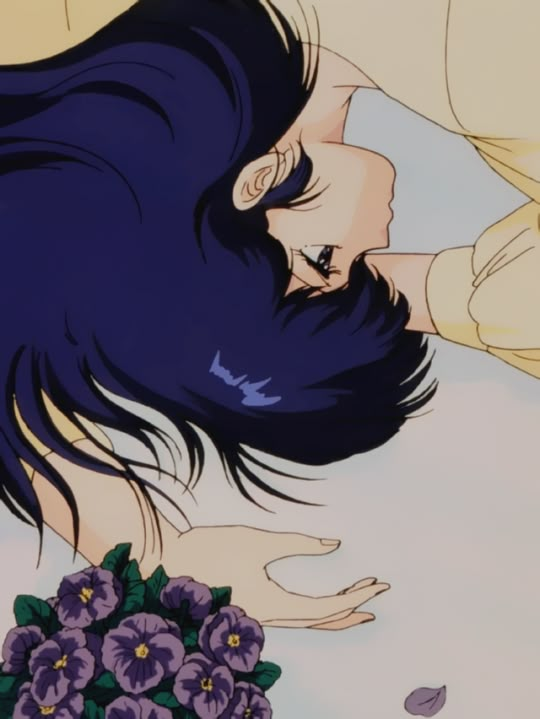 a woman laying on top of a bed with purple flowers next to her face and hair