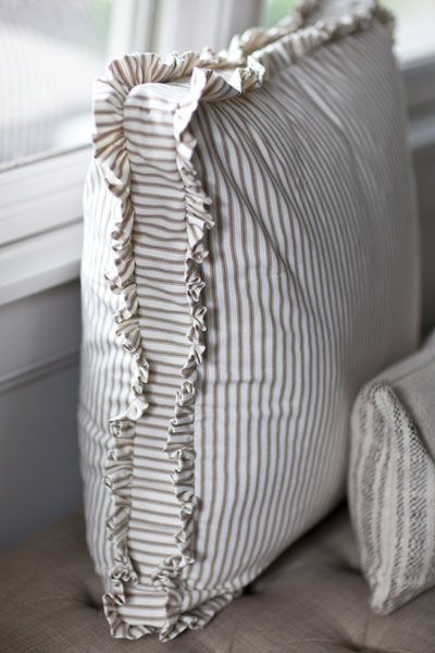 a pillow with ruffled edges sitting on a couch next to a window sill