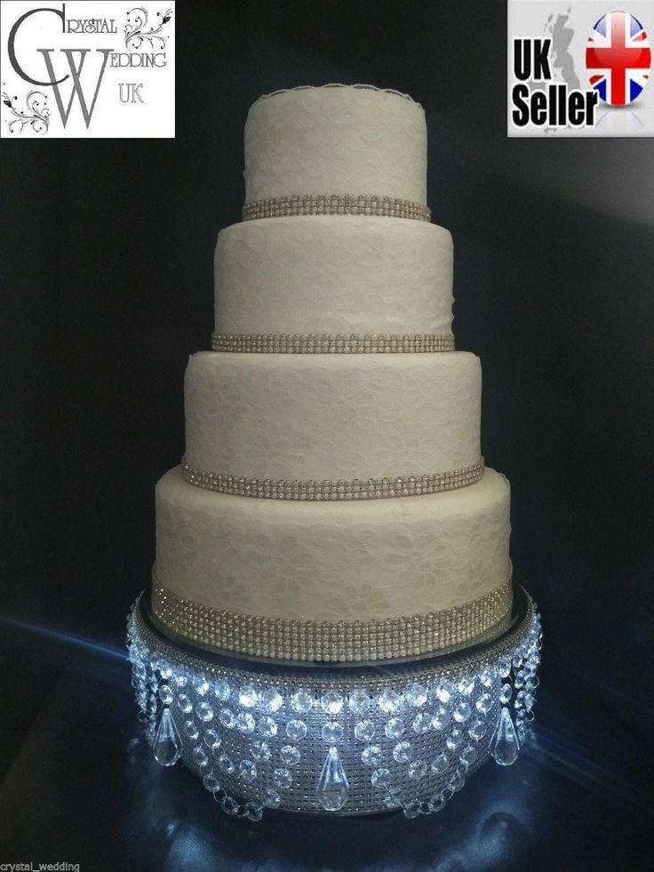 a three tiered wedding cake with beading on the bottom and sides is displayed