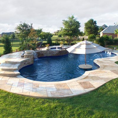 an outdoor pool surrounded by grass and umbrellas