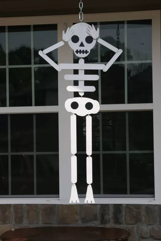 a paper skeleton hanging from the side of a window in front of a brick building