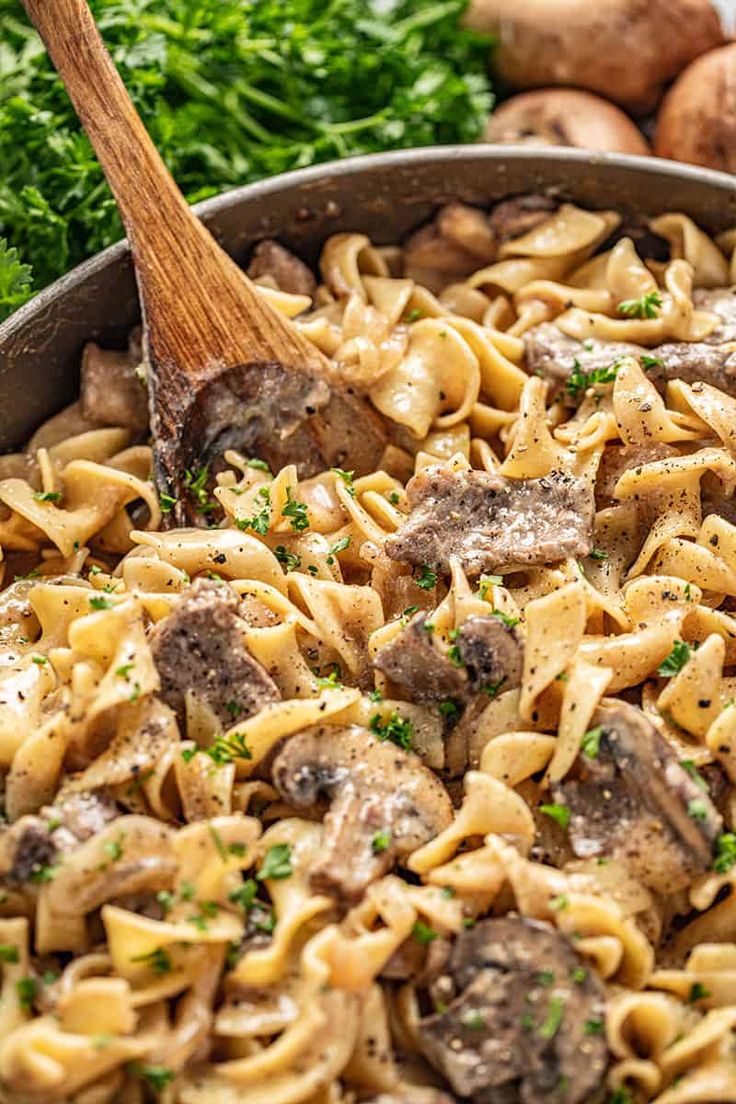 a skillet filled with pasta, mushrooms and parsley