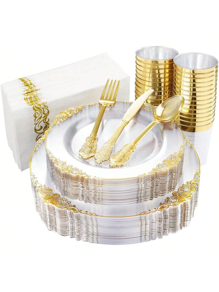 a set of gold and white dinnerware with napkins, forks, and cups