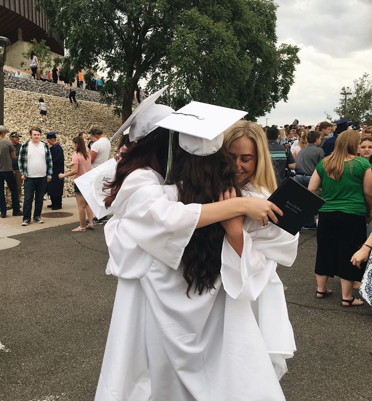 two women in graduation gowns hugging each other