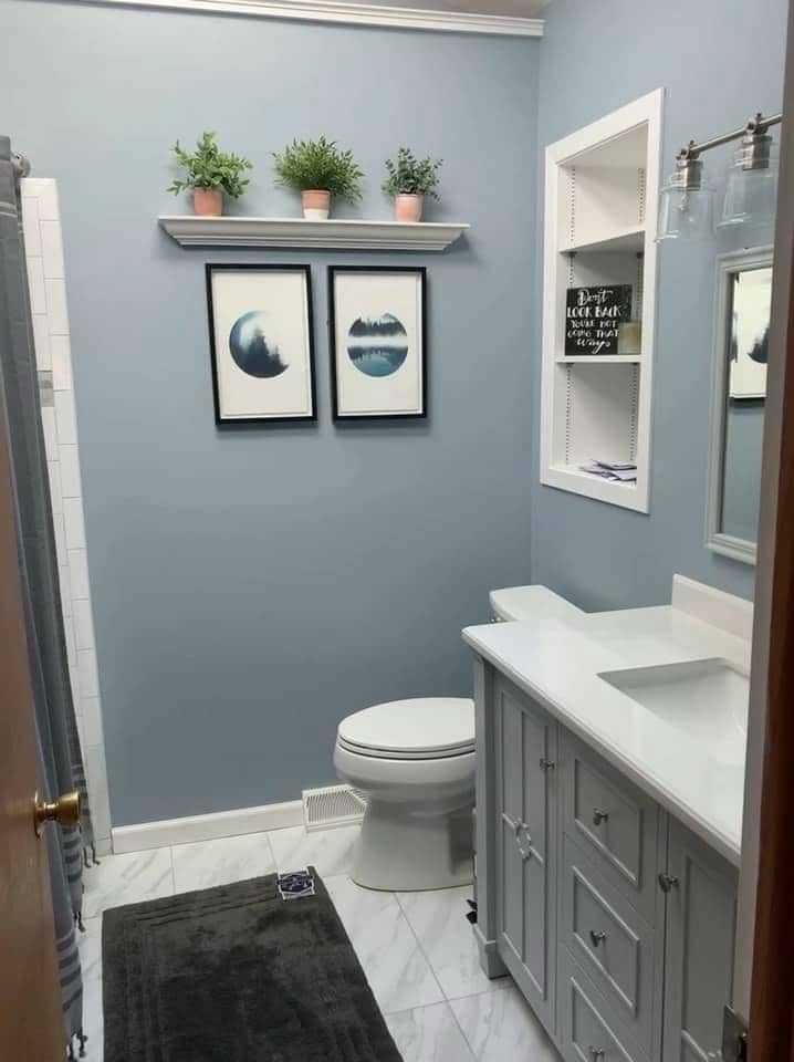 a white toilet sitting next to a bathroom sink under two framed pictures on the wall