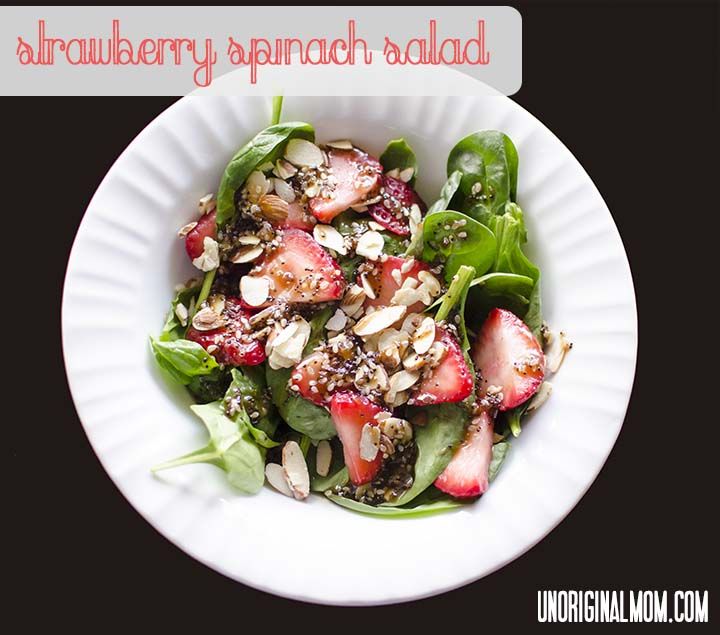 a salad with strawberries and almonds in a white bowl on a black background