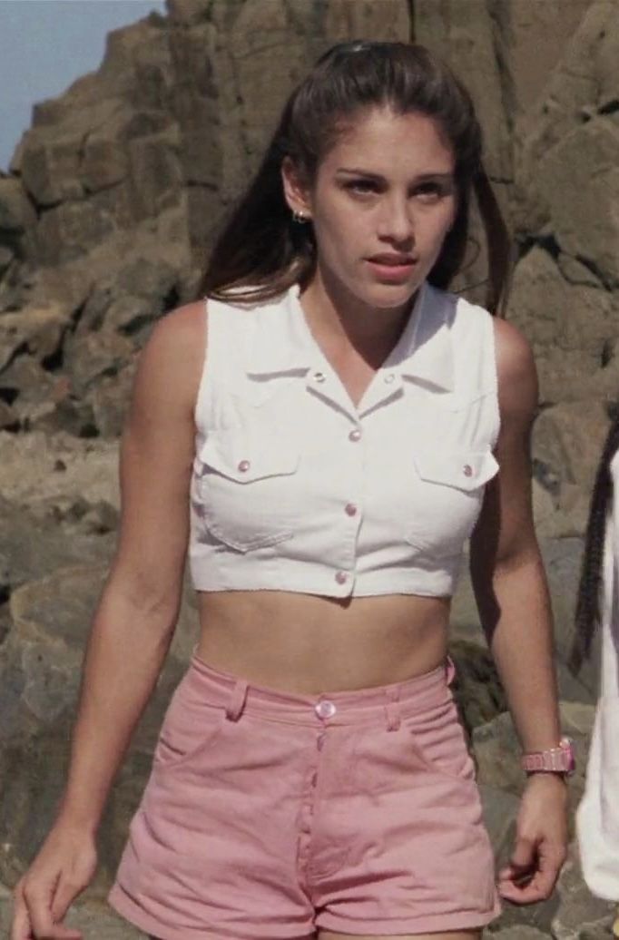 a woman in pink shorts standing next to a rock