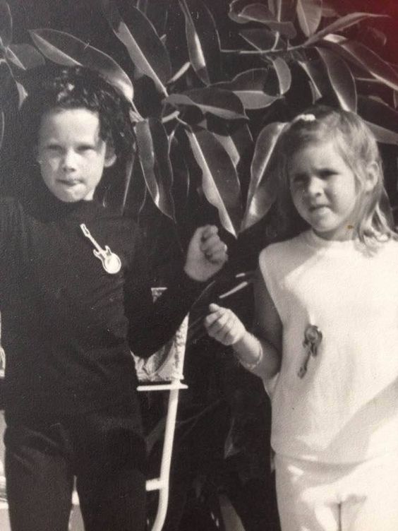 two young children standing next to each other in front of a wall with ribbons on it