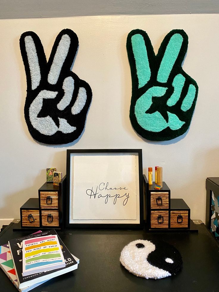 two peace signs are on the wall above a desk with books and other items in front of it