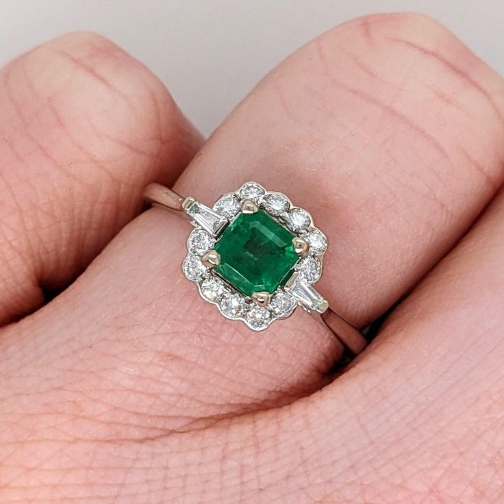 This lovely balanced ring design flaunts a gorgeous Zambian emerald with an incredible grass green hue. It's a great size for a daily accessory and looks stunning seated in a scalloped halo of diamonds, with two tapered baguette diamonds that create a more modern feel. A great piece of jewelry for May babies, and lovers of green and emeralds! This ring is made with solid 14K Gold and natural Earth mined SI / G-H diamonds. As listed, this ring is ready to ship. If you're interested in purchasing Classic Green Cluster Diamond Ring, Green Cluster Luxury Ring, Emerald Cluster Ring With Diamonds, Luxury Green Cluster Ring With Round Cut, Luxury Green Cluster Ring With Center Stone, Classic Green Diamond Cluster Ring, Green Emerald Cluster Ring With Diamonds, Green Cluster Diamond Ring, Classic Green Cluster Ring With Brilliant Cut