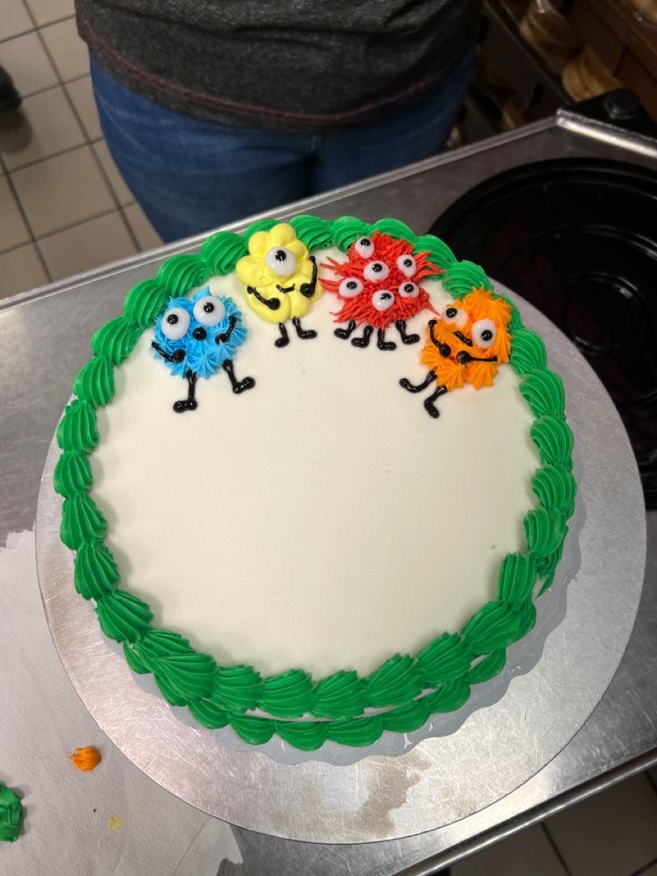 a decorated cake sitting on top of a metal counter next to a person holding a knife