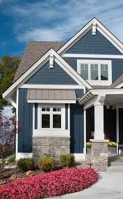 a house with blue siding and white trim on the front door, windows, and landscaping