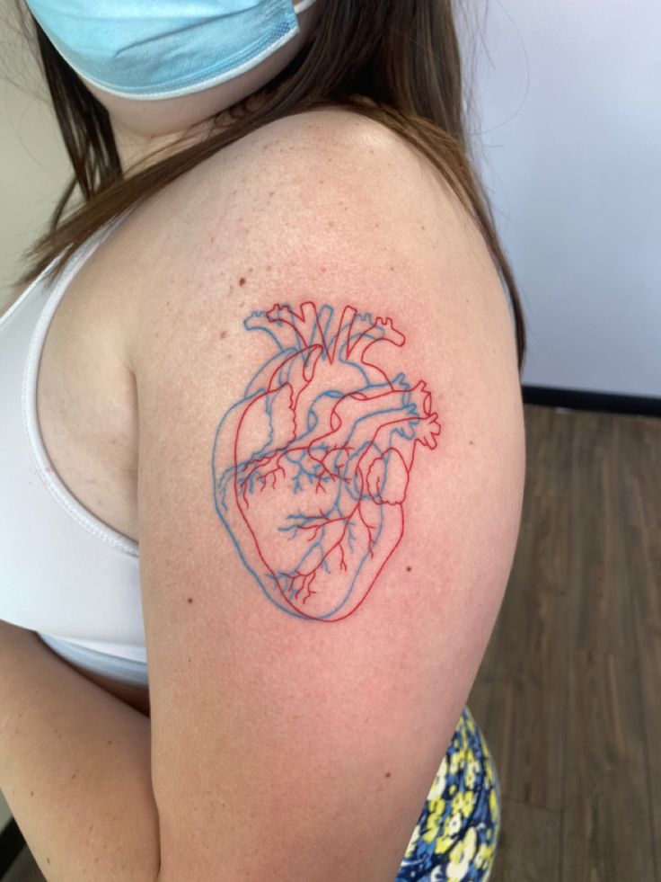 a woman with a heart tattoo on her arm and wearing a mask to protect it from the sun