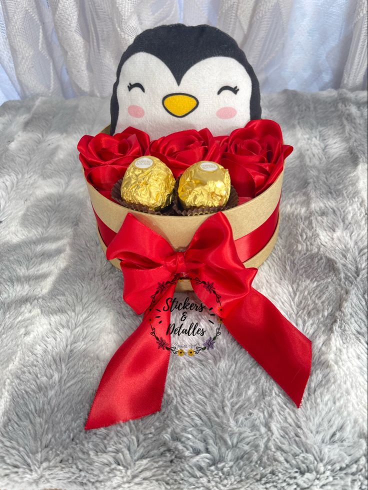 a stuffed penguin with roses and chocolates in it