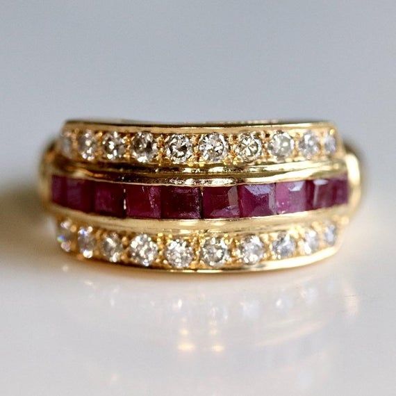 Two rows featuring 0.39 carats of diamonds sandwich a row of rubies. Ring size ranges from 5-8. Ruby Wedding Rings, Replica Jewelry, Ruby Ring Gold, Ruby And Diamond Ring, Gold Anniversary Rings, Indie Jewelry, Ruby Diamond Rings, Ruby Engagement Ring, Alternative Engagement Rings