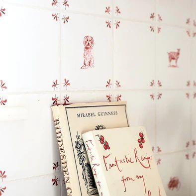 a stack of books sitting on top of a counter next to a white tiled wall