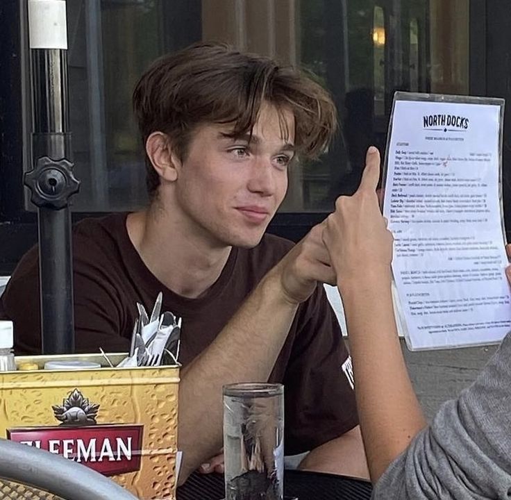 a man sitting at a table with a paper in his hand next to another person