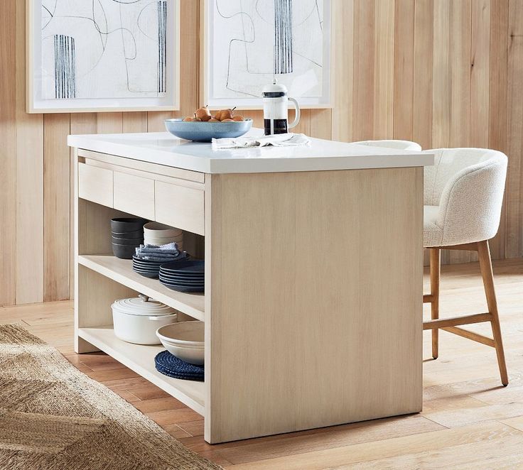 a kitchen island with plates and bowls on it in the middle of a living room